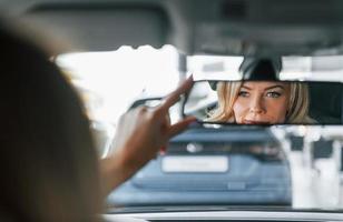 In the car. Woman in formal clothes is indoors in the autosalon photo