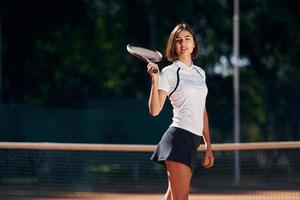 contra árboles en el fondo. la tenista femenina está en la cancha durante el día foto