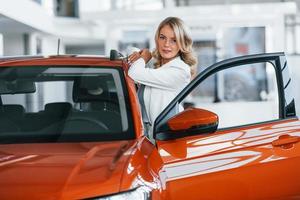 Opening the door. Woman in formal clothes is indoors in the autosalon photo