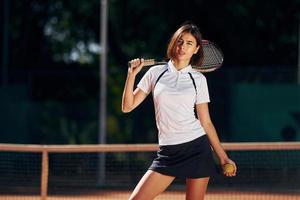 Female tennis player is on the court at daytime posing for a camera photo