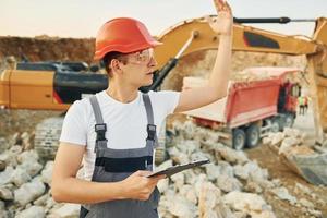 Management of project. Worker in professional uniform is on the borrow pit at daytime photo