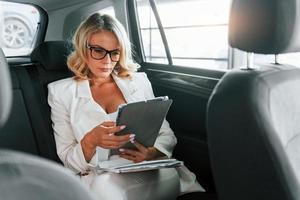 Working in the car. Woman in formal clothes is indoors in the autosalon photo