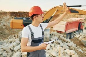 Management of project. Worker in professional uniform is on the borrow pit at daytime photo