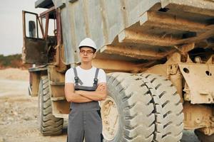 Near loading vehicle. Worker in professional uniform is on the borrow pit at daytime photo