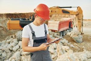 Management of project. Worker in professional uniform is on the borrow pit at daytime photo