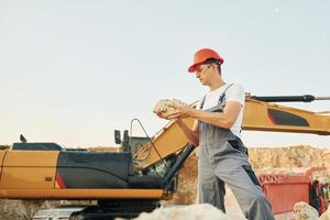 Holding documents in hands. Worker in professional uniform is on the borrow pit at daytime photo