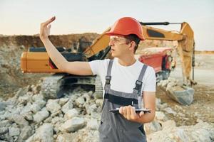 Management of project. Worker in professional uniform is on the borrow pit at daytime photo