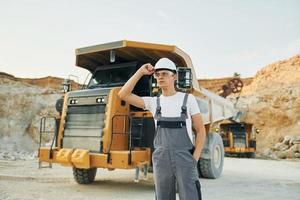 Posing for a camera. Worker in professional uniform is on the borrow pit at daytime photo