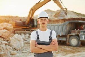 Standing with arms crossed. Worker in professional uniform is on the borrow pit at daytime photo
