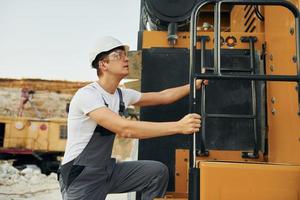Quality vehicle. Worker in professional uniform is on the borrow pit at daytime photo