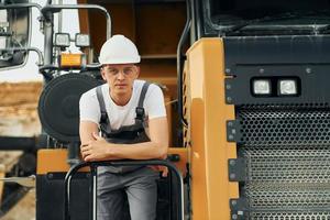 On the vehicle. Worker in professional uniform is on the borrow pit at daytime photo