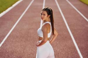 Rear view. Young woman in sportive clothes is exercising outdoors photo