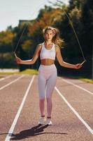 saltando en la pista de atletismo. mujer joven en ropa deportiva está haciendo ejercicio al aire libre foto