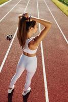 View from behind. Young woman in sportive clothes is exercising outdoors photo