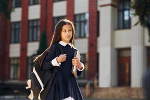 Schoolgirl is walking outside near school building photo