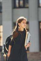 Against building. Schoolgirl is standing outside photo