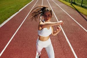 Practicing fight techniques. Young woman in sportive clothes is exercising outdoors photo