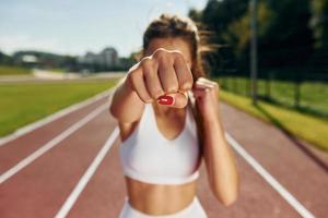 Practicing kickboxing. Young woman in sportive clothes is exercising outdoors photo