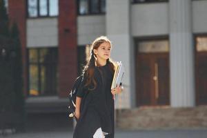 la colegiala está caminando afuera cerca del edificio de la escuela foto