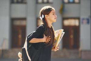 la colegiala está caminando afuera cerca del edificio de la escuela foto