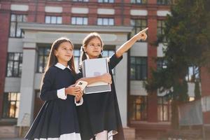 Two schoolgirls is outside together near school building photo