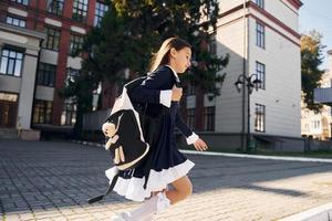 dando un paseo la colegiala está afuera cerca del edificio de la escuela foto