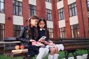 Conception of friendship. Two schoolgirls is outside together near school building photo