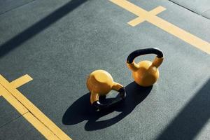 Weights painted in yellow color laying down on the ground in the gym photo