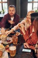 Free time. Group of young friends sitting together in bar with beer photo