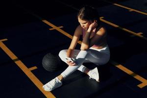 sentado con pelota de fitness. hermosa mujer joven con cuerpo delgado está en el gimnasio foto