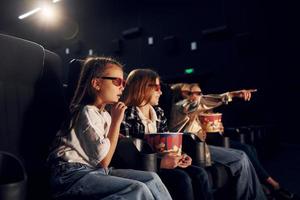 With popcorn. Group of kids sitting in cinema and watching movie together photo