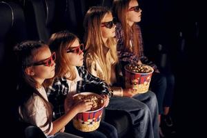 Facial expressions. Group of kids sitting in cinema and watching movie together photo