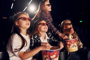 vista lateral. grupo de niños sentados en el cine y viendo películas juntos foto
