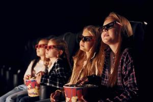 Facial expressions. Group of kids sitting in cinema and watching movie together photo