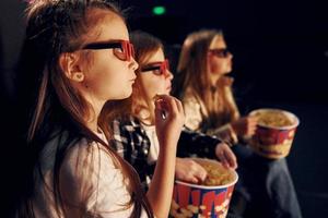 vista lateral. grupo de niños sentados en el cine y viendo películas juntos foto