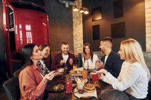 sentados juntos. grupo de jóvenes amigos en el bar con cerveza foto