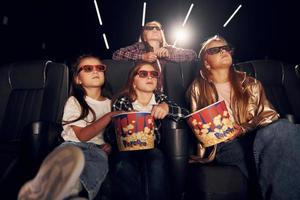 Front view. Group of kids sitting in cinema and watching movie together photo