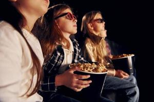 en ropa informal. grupo de niños sentados en el cine y viendo películas juntos foto