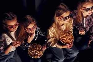 Friends watching movie together. Group of kids sitting in cinema photo