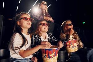 Front view. Group of kids sitting in cinema and watching movie together photo