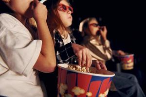 en ropa informal. grupo de niños sentados en el cine y viendo películas juntos foto