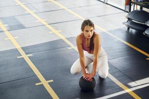 In white pants. Beautiful young woman with slim body type is in the gym photo