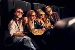 In dark room. Group of kids sitting in cinema and watching movie together photo