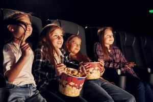 Relaxing and having fun. Group of kids sitting in cinema and watching movie together photo