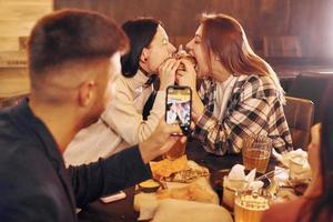 Eating food. Group of young friends sitting together in bar with beer photo