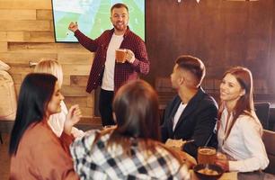 sosteniendo vasos. grupo de jóvenes amigos sentados juntos en el bar con cerveza foto