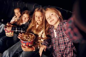 In dark room. Group of kids sitting in cinema and watching movie together photo