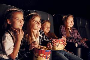 relajarse y divertirse. grupo de niños sentados en el cine y viendo películas juntos foto