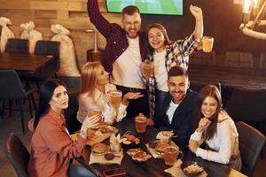 adentro en el bar. grupo de jóvenes amigos sentados juntos con cerveza foto