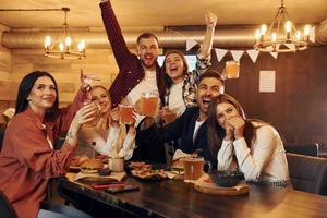 fanáticos del fútbol grupo de jóvenes amigos sentados juntos en el bar con cerveza foto